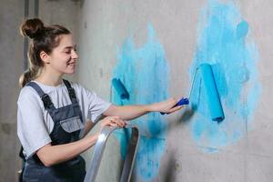 Casa decorazione Fai da te rinnovamento concetto. contento coppia nel vuoto camera di nuovo casa pittura parete insieme. marito e moglie Tenere dipingere rullo pittura parete con blu colore dipingere nel nuovo Casa. foto