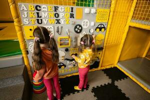 Due sorelle giocando con occupato tavola a bambini giocare centro. foto