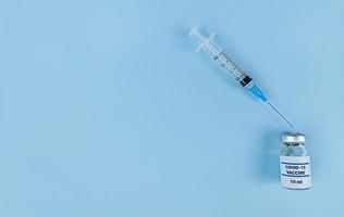 siringa monouso e bottiglia medica con vaccino contro il coronavirus su sfondo blu con spazio di copia foto