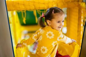 bambino ragazza ragazzo diapositiva a giallo terreno di gioco parco. bambino nel attivo divertimenti. foto