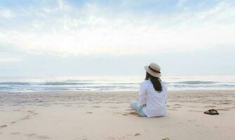 viaggio donna seduta su il spiaggia solo foto