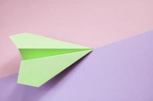 un aereo origami verde su sfondo diagonale viola e rosa foto