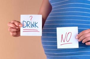 pancia di una donna incinta in una maglietta blu con le parole drink e no