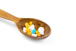 pillole medicinali e farmaci in cucchiaio di legno su sfondo bianco con spazio di copia foto