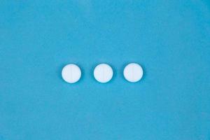 tre pillole rotonde bianche su sfondo blu foto