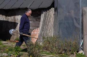 agricoltore maschio adulto porta una pala nel suo giardino foto