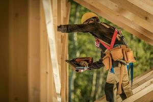 contraente Lavorando su di legno scheletro di il Casa con chiodo pistola foto