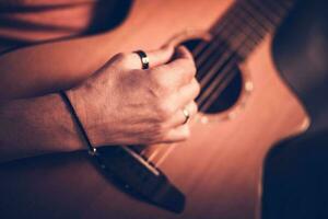 maschio musicista giocando su acustico chitarra mentre seduta fuori uso. foto