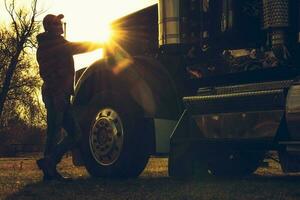 semi camion autista nel davanti di il suo veicolo durante panoramico tramonto foto