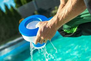 uomini rimozione chimico distributore a partire dal il suo piscina per caricare nuovo cloro tavoli foto