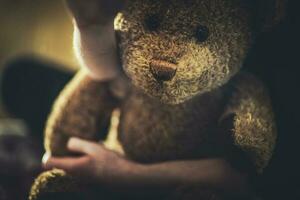 vicino Visualizza di orsacchiotto orso giocattolo nel bambino braccia. foto