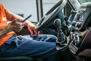 consegna camion autista navigazione Internet utilizzando il suo smartphone foto
