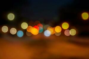 avvicinamento sfocato e bokeh riflessione illuminazione di macchine testa luci su il strada con traffico su notte tempo città. foto