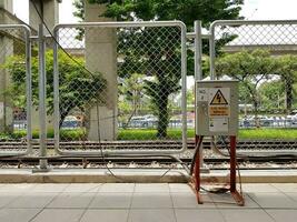 bangkok, Tailandia - Maggio 25, 2023 elettrico controllo Consiglio dei ministri installato su sentiero per temporaneo uso con inossidabile netto recinto e ferrovia treno sfondo foto