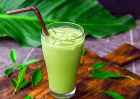 ghiacciato matcha latte macchiato, verde tè con latte nel un' bicchiere con ghiaccio su di legno foto