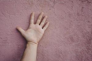 gesticolando con la mano sul muro rosa foto