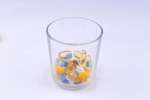 dose delle pillole colorate nel bicchiere foto