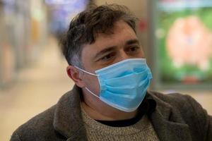 colpo alla testa di un uomo che copre il viso con una mascherina medica per proteggere il naso e la bocca foto