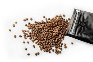 caffè in grani versato da un sacchetto nero su una superficie bianca foto