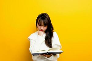 leggere un' prenotare, studia con il protagonista, cercare conoscenza, cibo per pensiero, ragazza lettura un' libro e sorridente. nel il foto studio giallo fondale