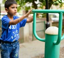 asiatico ragazzo fare routine esercizio nel società parco durante il mattina volta. carino poco ragazzo esercizio e Palestra per mantenere lui stesso in forma per vita. del bambino esercizio all'aperto sparare foto