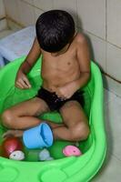 carino indiano ragazzo avendo bagno durante il estate vacanza stagione, carino asiatico bambino lavaggio nel un' bagno, ragazzo bagnarsi stile di vita concetto foto