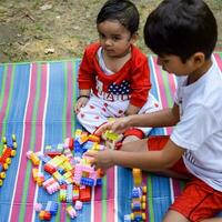 Due contento ragazzi nel società parco, contento asiatico fratelli chi siamo sorridente felicemente insieme. fratelli giocare all'aperto nel estate, migliore gli amici. bambino piccolo bambino ragazzo giocando con il suo contento fratello nel il giardino foto