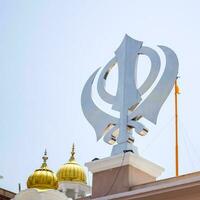 khanda sikh santo religioso simbolo a gurudwara Ingresso con luminosa blu cielo Immagine è prese a sorella ganj sahib gurudwara nel canni masticare, di fronte rosso forte nel vecchio delhi India foto