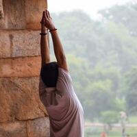 giovane indiano ispirato che fa asana yoga nel parco giardino di lodhi, nuova delhi, india. giovane cittadino che si esercita all'esterno e in piedi nella posa dell'angolo laterale dello yoga. fitness all'aperto e concetto di equilibrio vitale foto