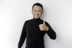 eccitato asiatico uomo indossare nero camicia dà pollici su mano gesto di approvazione, isolato di bianca sfondo foto