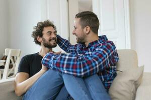 allegro giovane gay coppia seduta insieme. Due affettuoso maschio Gli amanti sorridente allegramente mentre Abbracciare una persona ogni Altro. giovane gay coupe essere romantico. foto