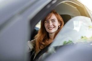 carino giovane signora contento guida macchina. Immagine di bellissimo giovane donna guida un' auto e sorridente. ritratto di contento femmina autista timone auto con sicurezza cintura foto