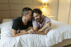 contento gay coppia dire bugie giù su il letto a casa, abbracciare e flirtare. lgbt gay coppia amore momenti felicità concetto foto