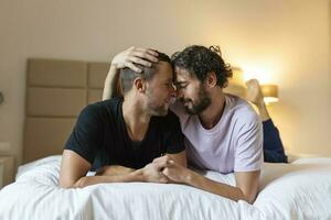 contento gay coppia dire bugie giù su il letto a casa, abbracciare e flirtare. lgbt gay coppia amore momenti felicità concetto foto