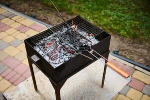 superiore Visualizza vuoto griglia grattugiare al di sopra di fiammeggiante carboncini su il barbeque griglia nel Giardino dietro la casa, pronto per collocazione marinato cibo. foto