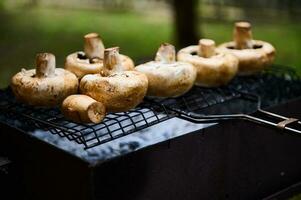 avvicinamento champignon funghi grigliate al di sopra di fiammeggiante carboncini mentre un' barbecue festa all'aperto. barbecue. picnic nel il natura foto