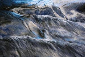 riflesso blu del cielo su un fiume che scorre foto