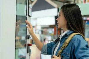 donna acquisto con un' vending macchina, tecnologia e consumo concetto. foto