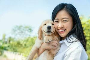 bellezza asiatico giovane donna Tenere cane d'oro cane da riporto razza su sua braccio Sorridi e felicità. amore animali domestici concetto. foto