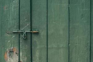 il vecchio e arrugginito chiavistello e serratura sulla porta di legno verde