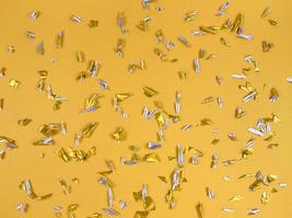 pezzi di lamina di coriandoli su sfondo giallo astratto sfondo festivo foto