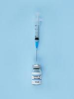 siringa monouso e bottiglia medica con vaccino contro il coronavirus su sfondo blu