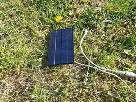 solare pannello per ricarica un' smartphone su il erba foto