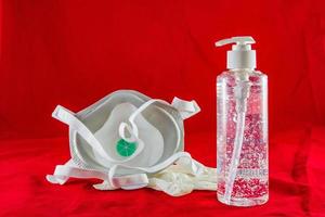 gel igienizzante guanti in lattice bianco e maschera su rosso concetto di protezione contro l'inquinamento da virus influenzale e coronavirus foto