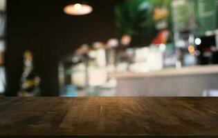 vuoto buio di legno tavolo nel davanti di astratto sfocato bokeh sfondo di ristorante . può essere Usato per Schermo o montaggio il tuo prodotti.mock su per spazio. foto