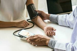 medico assistenza sanitaria. professionale medico medico nel bianca uniforme toga cappotto colloquio consulenza paziente rassicurante il suo maschio paziente porzione mano foto