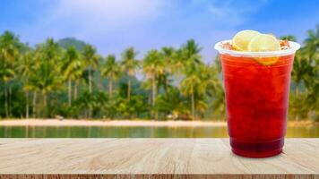 ghiacciato tè e Limone fette su di legno tavolo con spiaggia paesaggio natura sfondo, estate bevande con ghiaccio foto