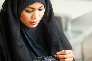 giovane arabo burka rivestito donna cucire un' zucchetto foto
