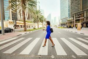 bellissimo africano donna attraversamento il strada su un' strada di dubai foto
