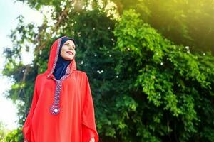 bellissimo musulmano caucasico donna indossare rosso vestito e hijab nel il parco foto